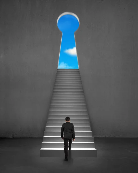 Businessman climbing on stair to key shape door with blue sky — Stock Photo, Image