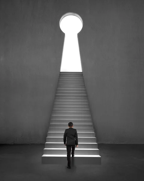 Geschäftsmann klettert auf Treppe zu Schlüsselform Tür Beton backgro — Stockfoto