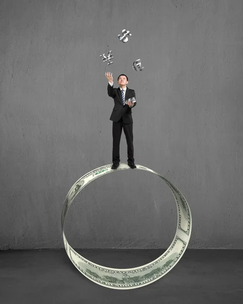 Businessman throwing and catching money symbols on money circle — Stock Photo, Image