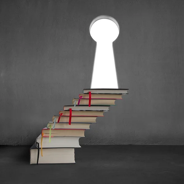 Stack of books with key shape door on concrete wall — Stock Photo, Image