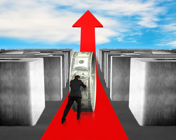 Man pushing money on growing red arrow through maze — Stock Photo, Image