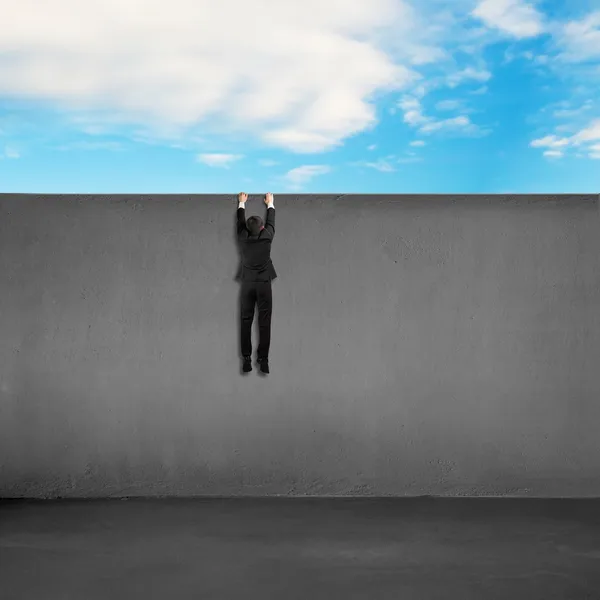 Trying to climb over wall with blue sky background — Stock Photo, Image