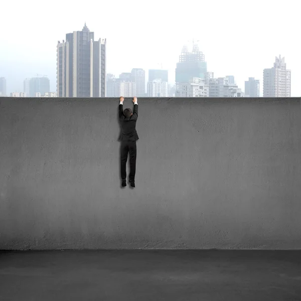 Businessman trying to cross over wall with city view — Stock Photo, Image