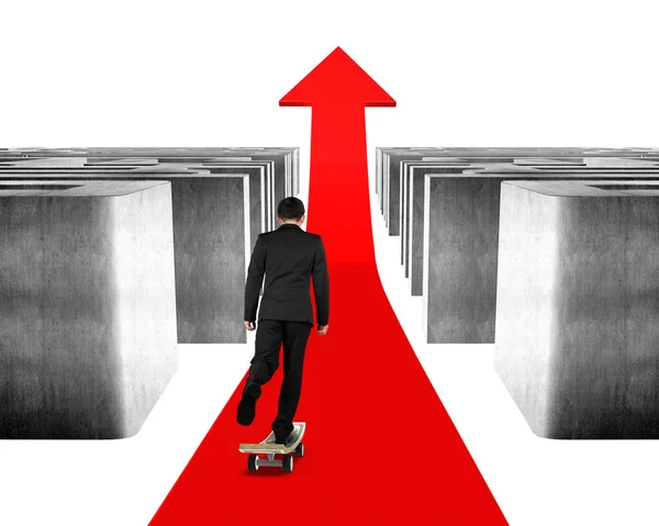 Businessman skateboarding through maze on red arrow — Stock Photo, Image