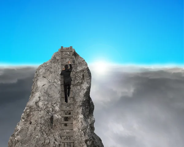 Geschäftsmann klettert mit Sonnenaufgang auf felsigen Berg — Stockfoto