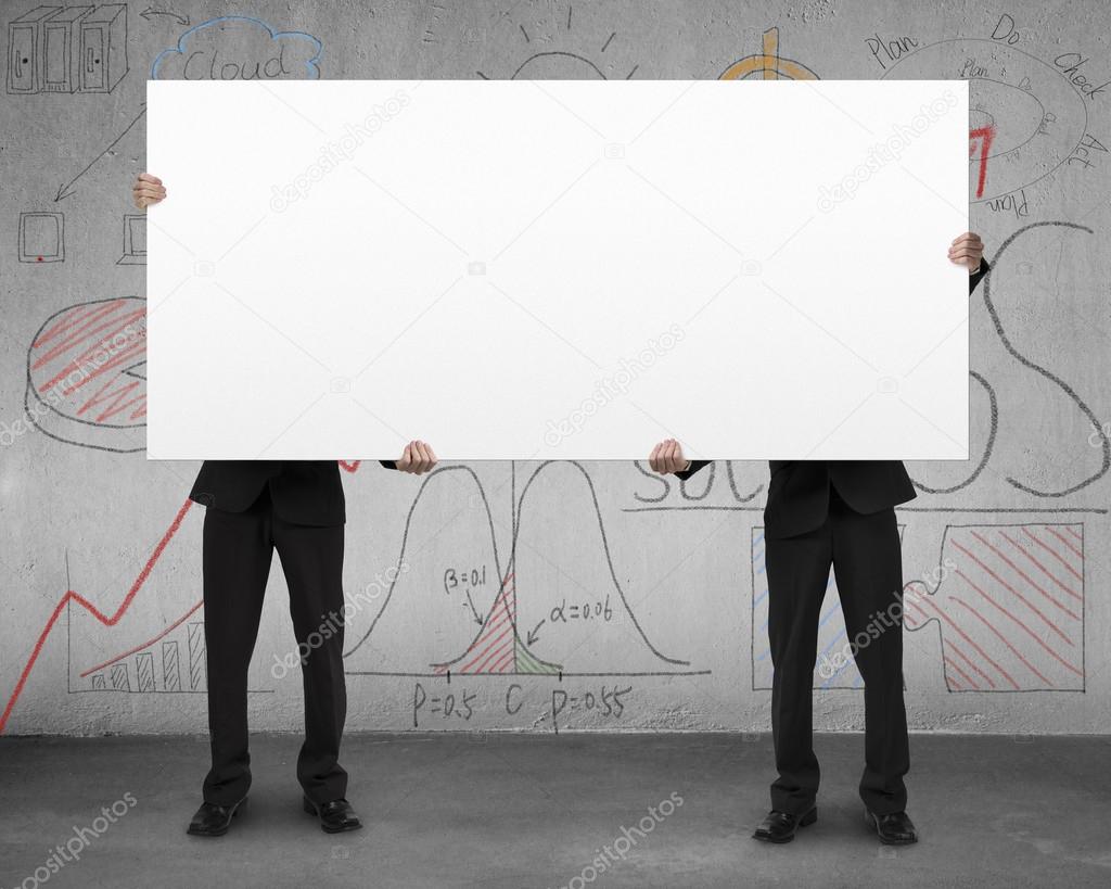 Two man holding board with business doodles on wall