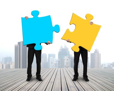Two men holding puzzles on wooden floor clipart