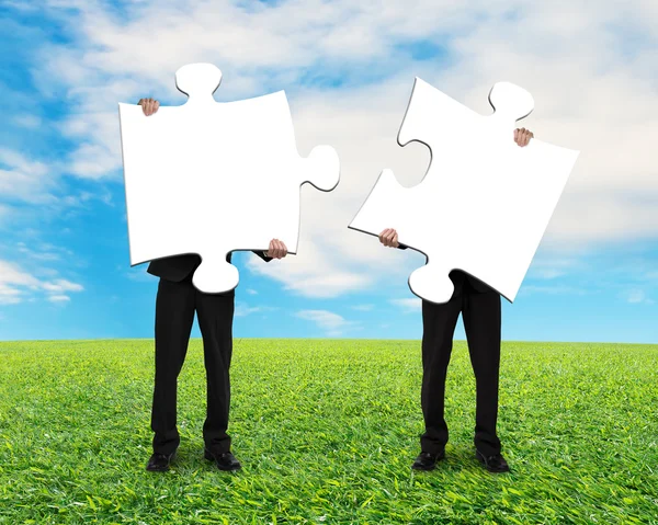 Two men holding blank puzzles on grass ground — Stock Photo, Image