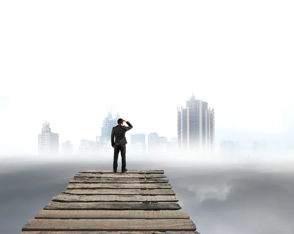 Uomo d'affari che guarda la città con nuvoloso sotto — Foto Stock