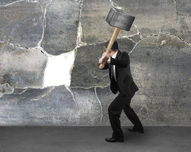 Businessman holding sedgehammer to crack wall clipart
