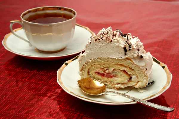 Cup of tea with the spoon and a slice of pie on red background — Stock Photo, Image