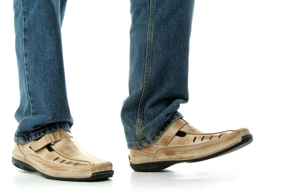 Человеческая нога в коричневой кожаной обуви и джинсах — стоковое фото