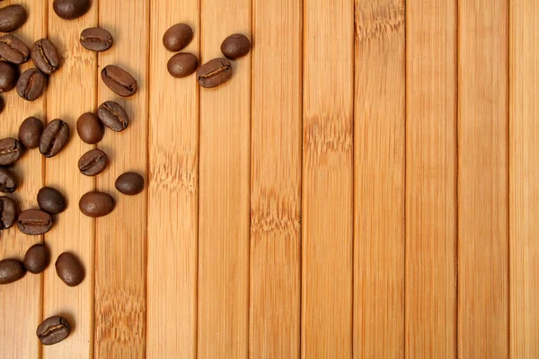 Grains of coffee on a carpet made of a bamboo — Stock Photo, Image