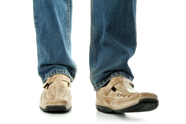 Человеческая нога в коричневой кожаной обуви и джинсах — стоковое фото