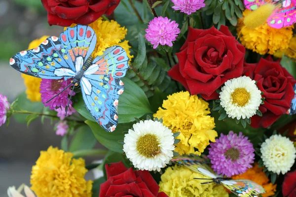 Flowers and artificial butterfly — Stock Photo, Image