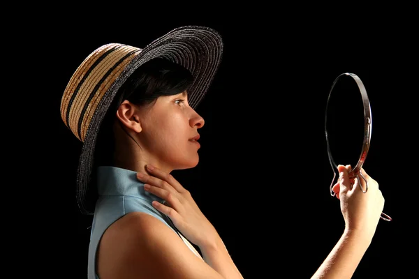 Молодая женщина в соломенной шляпе смотрит в зеркало — стоковое фото