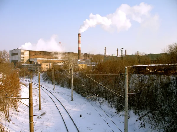 Lit de rail recouvert d'une neige près d'une usine métallurgique — Photo