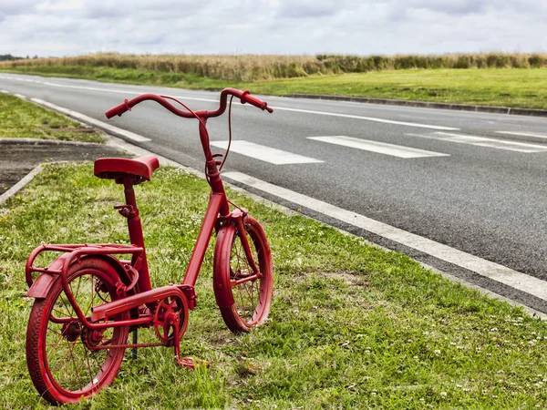 Красный велосипед на обочине дороги — стоковое фото