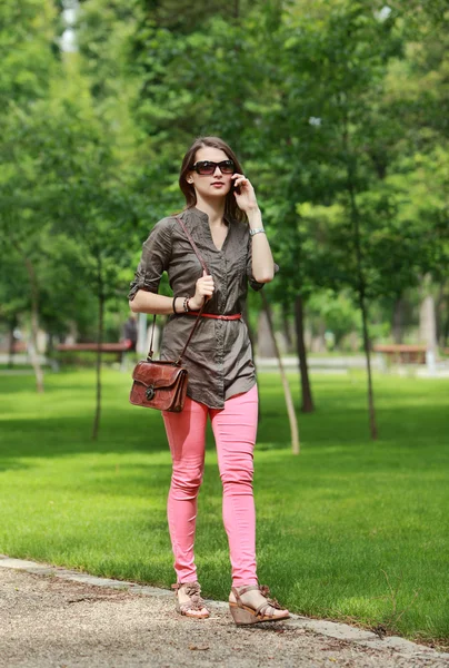 Mujer joven al teléfono caminando en un parque — Foto de Stock