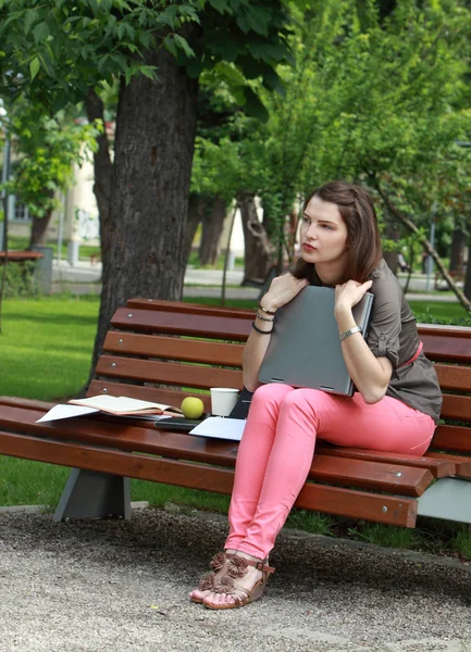 Mujer joven con un ordenador portátil en el parque — Foto de Stock