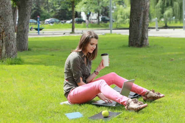 Ung kvinna med dator i en stadspark — Stockfoto