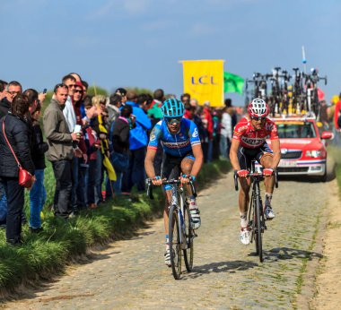 Carrefour de l 'Arbre, Fransa-Nisan 13, 2014: Paris-Roubaix bisiklet yarışı sırasında Camphin-en-Pvle kasabasındaki ünlü kaldırım taşı sektörü Carrefour de l' Arbre 'de iki bisikletçi. 