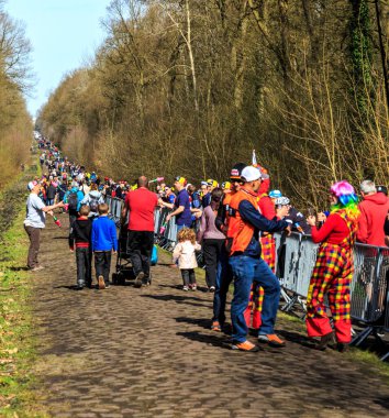 Wallers-Arenberg, Fransa - 12 Nisan 2015: Paris-Roubaix bisiklet yarışı sırasında bisikletçilerin geçmesinden önce ünlü asfalt sektörü Arenberg uçurumunda yürüyen insanlar (Trouee d 'Arenberg).
