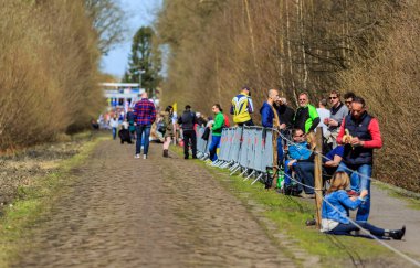 Wallers-Arenberg, Fransa - 12 Nisan 2015: Paris-Roubaix bisiklet yarışı sırasında bisikletçilerin geçmesinden önce ünlü asfalt sektörü Arenberg uçurumunda yürüyen insanlar (Trouee d 'Arenberg).