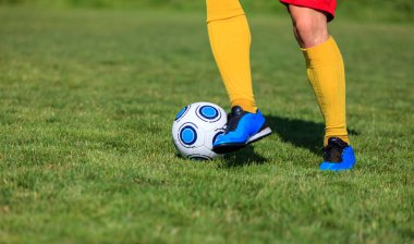 Top süren bir futbolcunun ayaklarının yakın plan görüntüsü.