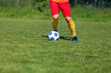 Top süren bir futbolcunun ayaklarının yakın plan görüntüsü.