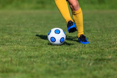 Top süren bir futbolcunun ayaklarının yakın plan görüntüsü.