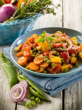 mixed sauteed vegetables on dish over wood background clipart