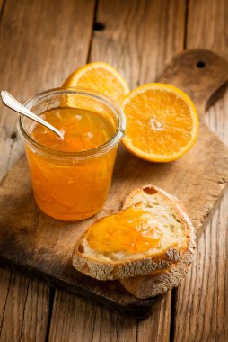 Ahşap zemin üzerinde ekmek olan portakal reçeli.