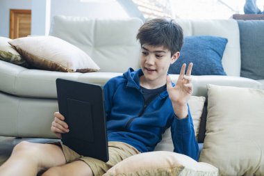 Evde online iletişim kurmak için tablet kullanan çocuk.