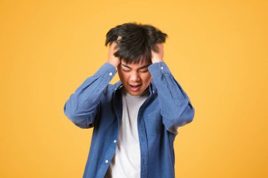 Baş ağrısı çeken yakışıklı genç bir adam. Acı ve migren yüzünden çaresiz ve stresli. Ellerini başının üstüne koy..