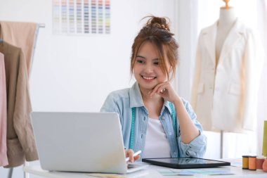 Moda tasarımcısı stüdyoda çalışıyor, çizim kesme, dikiş elbise