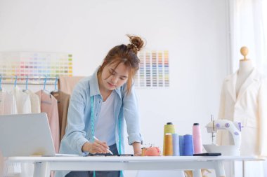 Moda tasarımcısı stüdyoda çalışıyor, çizim kesme, dikiş elbise