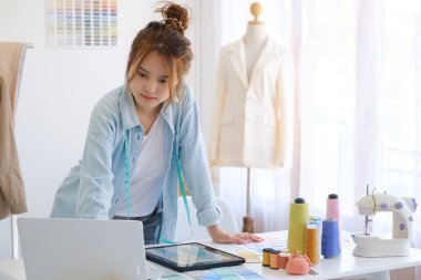 Moda tasarımcısı stüdyoda çalışıyor, çizim kesme, dikiş elbise