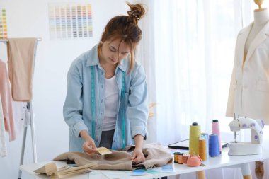 Moda tasarımcısı stüdyoda çalışıyor, çizim kesme, dikiş elbise