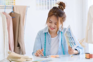 Moda tasarımcısı stüdyoda çalışıyor, çizim kesme, dikiş elbise