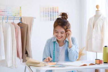 Moda tasarımcısı stüdyoda çalışıyor, çizim kesme, dikiş elbise