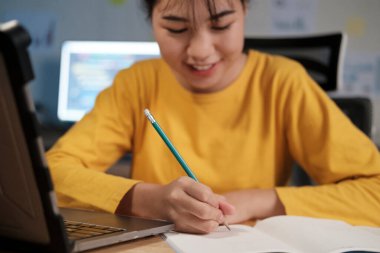 Genç Asyalı bir kadın gece evde çalışıyor ve öğreniyor..