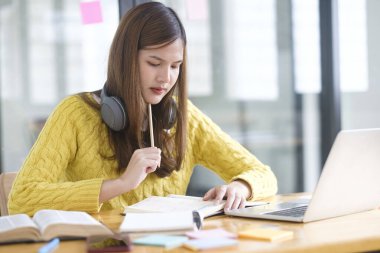 Bilgisayar ve mobil cihaz kullanan genç bir kolaj öğrencisi. Eğitim ve çevrimiçi öğrenim. 
