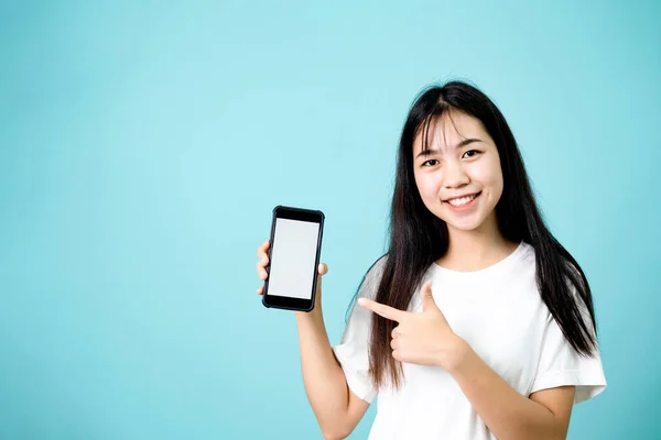 Porträt einer glücklichen jungen Frau, die auf den leeren weißen Bildschirm ihres Smartphones zeigt — Stockfoto