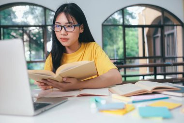 Çevrimiçi bilgisayar ve mobil aygıt kullanan genç kolaj öğrencisi.