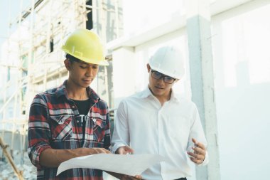 İnşaat alanında çalışan mühendisler toplantı yapıyor ve tartışıyorlar..