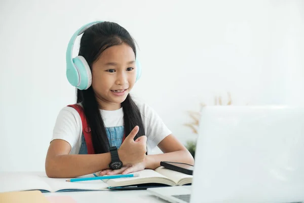 Fernstudium. Kind lächelt, Daumen hoch und lernt zu Hause online. — Stockfoto