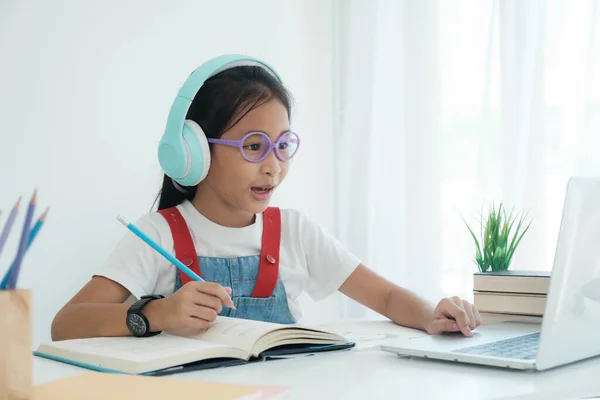 Mooie stijlvolle school meisje studeren huiswerk tijdens online les thuis,, studeren online video call leraar. — Stockfoto