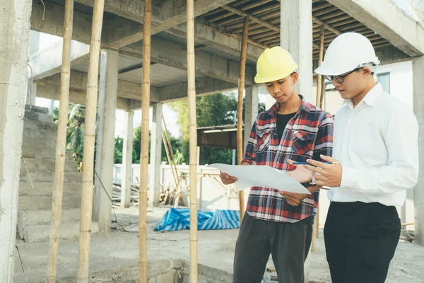 İnşaat alanında çalışan mühendisler toplantı yapıyor ve tartışıyorlar..