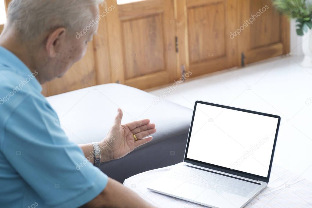 Smiling senior man reading news on digital tablet. Cheerful excited mature male using portable computer at home.